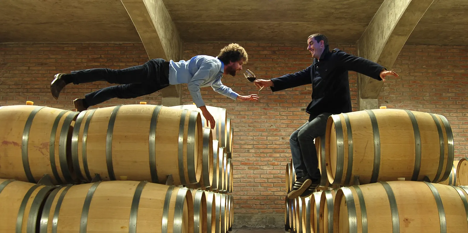 Los dos enólogos brindando sobre las barricas de la bodega